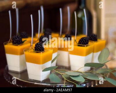 Gelbe und weiße gel Desserts mit Brombeeren mit Eukalyptus Branchen und mit Löffel in Ihnen eingerichtet Stockfoto