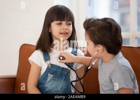 Glückliche Schwester und Bruder spielen Arzt gemeinsam zu Hause. Stockfoto