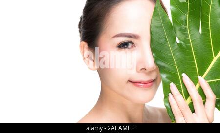 Close-up Studio shot, schöne junge Frau mit sauberem frische Haut Holding grüne Blätter. Ein Produkt vorschlagen. Gesten für Werbung auf Wh isoliert Stockfoto