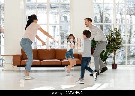 Mit verbundenen Augen, Mutter und Vater mit Kindern spielen Verstecken und Suchen. Stockfoto