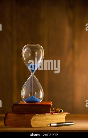 Sanduhr am alten Buch im Morgenlicht. Zeit, ein Buch zu lesen. Stockfoto