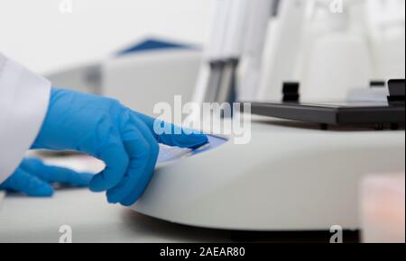Hände in Latex Handschuhe das Drücken von Tasten auf Lab Maschine Stockfoto