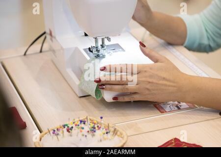 Bis - Weibliche maßgeschneiderte Arbeiten mit Nähmaschine. professionelle Frau Hände während des Nähens arbeiten mit Garn auf der Nähmaschine zu schließen. Selektive konzentrieren. Stockfoto