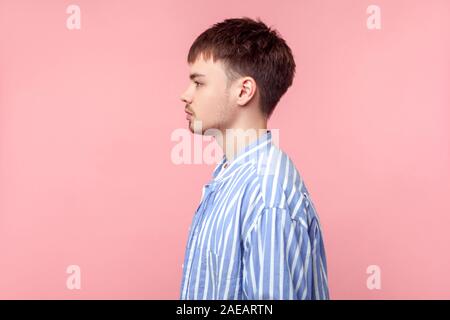 Seitenansicht Porträt der jungen zuversichtlich braunhaarige Mann mit dem kleinen Bart und Schnurrbart in lässig-gestreiften Hemd beiseite mit ernsten Gesicht expressio Stockfoto