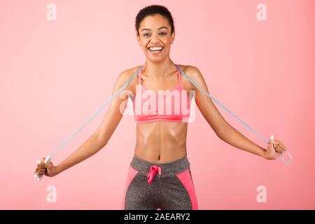 African American Woman Holding Springseil Posing über rosa Hintergrund Stockfoto