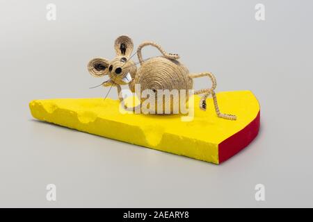Lustige Maus liegt auf einem Stück Käse. Handarbeit von Garn. Stockfoto