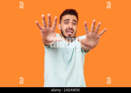 Ich habe Angst! Portrait von Angst Angst brünett Mann mit Bart im Weißen t-shirt machen Angst Geste mit erhobenen Händen, Panikattacken Konzept. Ich Stockfoto