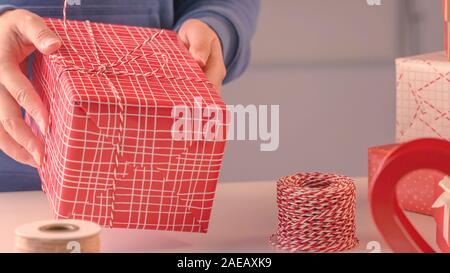 Eine junge Frau in Blau ist Umhüllung, Verpackung Weihnachtsgeschenk für Kinder von schönen, roten, weißen Wrapper mit glitzernden Licht, Lifestyle. Stockfoto