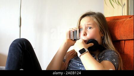 Mädchen benutzt moderne Technologie. Ein kleines Mädchen, das mit dem Handy spielt. Das Kind verbringt seine Freizeit mit moderner Technologie. Stockfoto