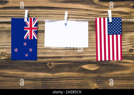 Hängenden Flaggen von Neuseeland und der Vereinigten Staaten zu Seil mit wäscheklammer mit Kopie Raum befestigt auf weißem Papier auf Holz- Hintergrund. Diplomatischen Stockfoto