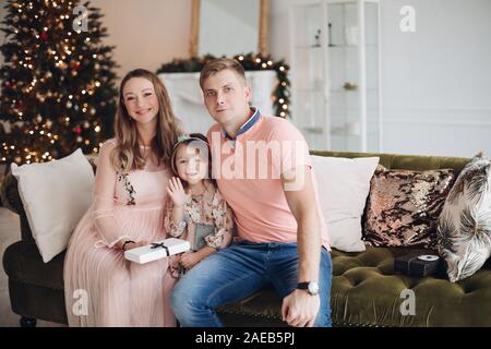 Lächelnde Mutter geben Geschenkbox süsse kleine Tochter während der Weihnachtsfeier Abendessen Gefühl der Liebe Stockfoto