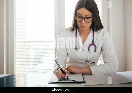 Medizinische Aufzeichnungen junger Arzt füllen Patienten Stockfoto