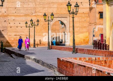 Die Menschen in der alten Stadt von Marrakesch wandern unter den großen alten Mauern und historischen Gebäuden. Stockfoto