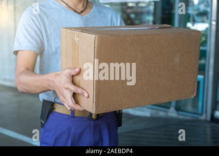 Junge delivery man Handhabung Pakete bestellen. Versand und Logistik im e-commerce Industrie liefern durch Postboten. Stockfoto