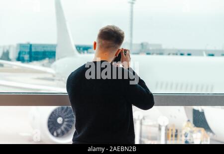 Junge blogger Fotograf macht ein Foto von Jet an der Start- und Landebahn vor. Konzept des modernen Reisens und Blogging. Stockfoto