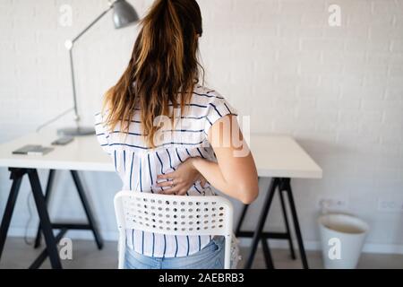 Überforderten Frau mit Rückenschmerzen im Büro mit schlechter Haltung Stockfoto
