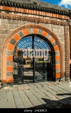 Gyumri, Armenien, 05. September 2019: Bogen mit einer gemusterten Grenze von Schwarz und Rot mit schwarzem Tuff oval schmiedeeisernen Toren auf den Zaun des Hauses Dzito Stockfoto