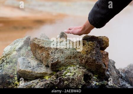 Mann hält eine Hand über Dampfenden Solfataren im Bereich Geothermie Namaskard, Island. Stockfoto