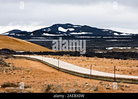 Ein Pfad aus Holz durch die Lava Landschaft des Leirhnjukur Lavafelder in Island führt. Stockfoto