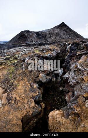 Eine tiefe Schlucht mit einem Vulkan Krater im Hintergrund, in Island gesehen. Stockfoto