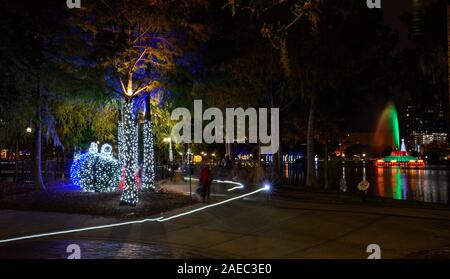 Menschen gehen durch neue Urlaub Dekorationen am Lake Eola Park in der Innenstadt von Orlando, Florida. Stockfoto