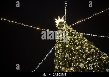 Stilvolle Weihnachten Baum mit goldenen Lichter und leuchtende Stern oben, Ketten von hellen und dunklen Hintergrund Stockfoto