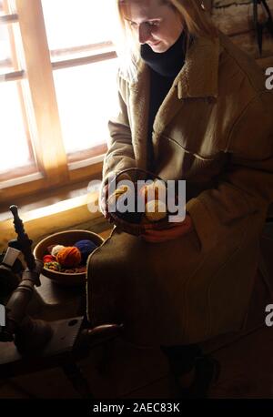 Strickende Frau wolle in einem Korb liegen. Retro Mode stricken Garn und Stricknadeln aus Holz. Holzhaus und Kleidung im Vintage Style. Stockfoto