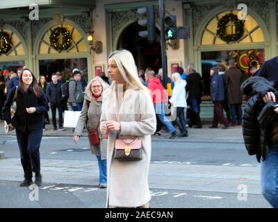 Attraktive junge Frau im Winter Mantel & Masse von Menschen außerhalb Fortnum & Mason Store zu Weihnachten im Piccadilly London England UK KATHY DEWITT Stockfoto