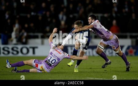 Verkauf Haifische' Chris Ashton wird von Exeter Häuptlinge' Joe Simmonds (links) und Dave Dennis (rechts), während die Heineken Europacup Pool zwei Gleichen an den AJ Bell Stadium, Verkauf in Angriff genommen. Stockfoto