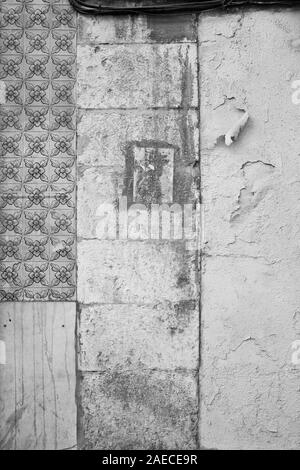 Vorderansicht eines alten Wand mit blasser Keramik Kacheln (AZULEJOS), schmutzig und verwitterten Steinen und die Farbe blätterte von den Wänden. Hintergrund in Schwarz und Weiß. Stockfoto