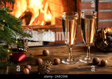 Weihnachten Komposition - Zwei Gläser mit Champagner auf einer hölzernen Tisch in der Nähe eines Weihnachtsbaumes in einem Raum mit einer brennenden Kamin. Stockfoto