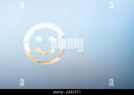 Lächelndes Gesicht auf einem gefrorenen Fenster gemalt, Winter Spaß, Jahreszeit und hoffen, Konzept, Text, Copyspace. Stockfoto
