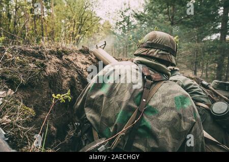 Re-enactors gekleidet, wie Deutsche Wehrmacht Infanterie Soldaten im Zweiten Weltkrieg versteckt Sitzen mit deutschen Hand - Anti-tank Granatwerfer Waffe in einem gehalten Stockfoto