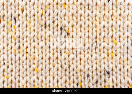 Textur aus Wolle Stricken beiger Stoff durchsetzt mit gelbem Garn. Pullover Hintergrund Nahaufnahme anzeigen Stockfoto