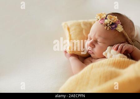 Neugeborenes Baby auf den gelben Kissen mit einem Rim auf dem Kopf Stockfoto