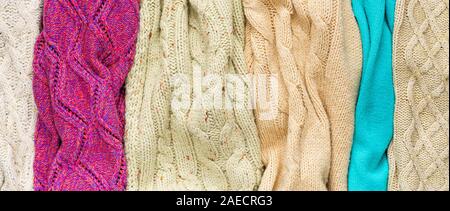Verschiedene Bunte gestrickte Pullover legt Seite an Seite als Hintergrund Stockfoto