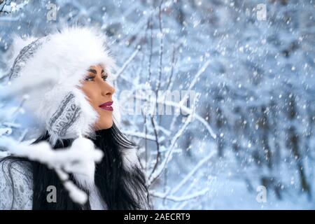 Schöne Mädchen in der warme Winter hat posiert im Winter fores in der Nähe von Bäumen, Schnee. Positives Modell weg schauen, bewundern der Natur im Winter sonniger Tag. Konzept der Winterbekleidung. Stockfoto