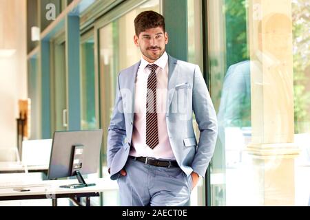 Portrait von selbstbewussten jungen Geschäftsmann in Anzug und Krawatte tragen, während sie sich im Büro. Stockfoto
