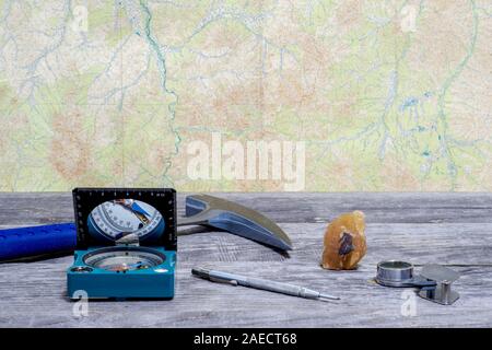 Tools Geologe auf einem Holztisch auf dem Hintergrund einer topographischen Karte. Hintergrund. Stockfoto