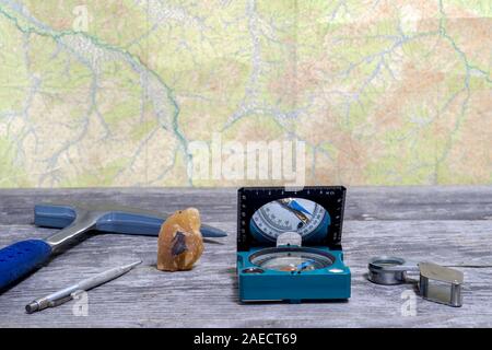 Tools Geologe auf einem Holztisch auf dem Hintergrund einer topographischen Karte. Hintergrund. Stockfoto