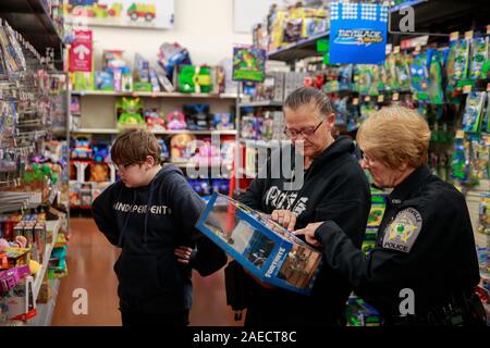 Elllettsville Polizeioffizier Gail Jones, rechts, hilft Kim Kent, das Einkaufen ist mit ihrem Enkel LeBron Kent, links, beim Geschäft mit einer Spindel, Sonntag, Dezember 8, 2019 in Bloomington, Ind. Mitglieder der Strafverfolgung von Monroe County einschließlich der Mitglieder der IUPD, Bloomington Police Department, Monroe County Sheriff's Office und Ellettsville Polizei Abteilung im Falle von der Don Owens Memorial brüderliche Auftrag der Polizei Lodge 88 teilgenommen. (Foto von Jeremy Hogan/Die Bloomingtonian) Stockfoto