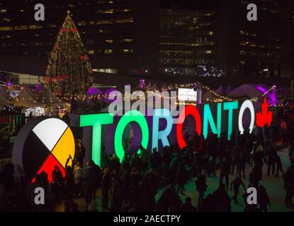 TORONTO, KANADA 12 23 2018: Nacht Blick auf Nathan Phillips Square in der kanadischen Stadt Toronto mit Menschen Spaß auf der Eisbahn in Stockfoto