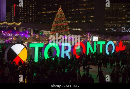 TORONTO, KANADA 12 23 2018: Nacht Blick auf Nathan Phillips Square in der kanadischen Stadt Toronto mit Menschen Spaß auf der Eisbahn in Stockfoto