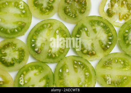 Solanum Lycopersicum. Scheiben von Unreife, grüne Tomaten auf weißem Hintergrund. Stockfoto