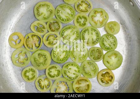 Solanum Lycopersicum. Scheiben der unreife grüne Tomaten n der Pfanne. Stockfoto