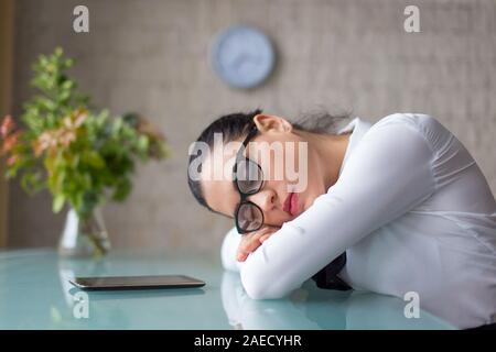 Überarbeitete Mitarbeiter schlafen auf dem Schreibtisch im Büro Stockfoto