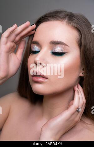 Nahaufnahme von fashion model junge Frau in trendigen Make-up. Auge Modelle mit bunten Glitter auf den Augenlidern Stockfoto