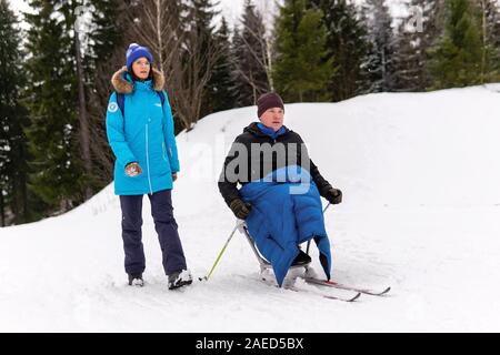 Perm, Russland - 07 Dezember, 2019: Sportler Skifahrer mit Behinderung Training im Freien im Winter mit einem begleitenden Stockfoto