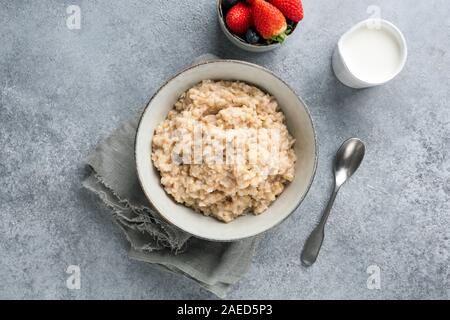 Gesundes Frühstück brei Hafer oder Haferflocken in Schüssel auf konkreten Hintergrund, Ansicht von oben geschossen. Saubere Konzept Essen Stockfoto