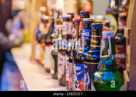 Ausgewählte Fokusansicht verschiedener Marken von Bierflaschen aus dem Handwerk auf der Theke des Fests auf dem Weihnachtsmarkt. Stockfoto